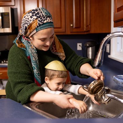 Mother washing son's hands with washing cup 2